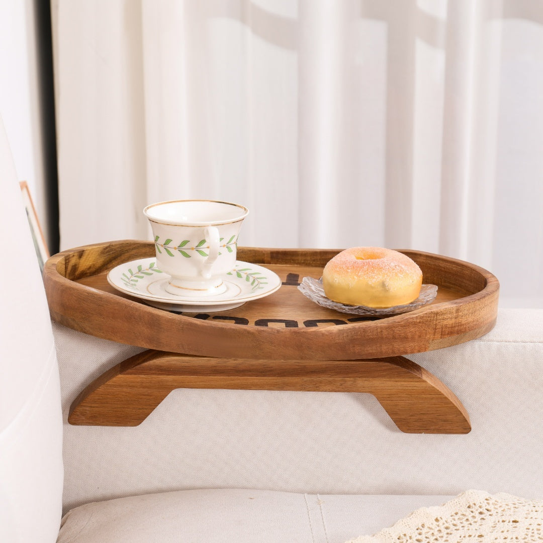 Plateau en bois d'acacia sur un accoudoir de canapé avec tasse de thé et beignet