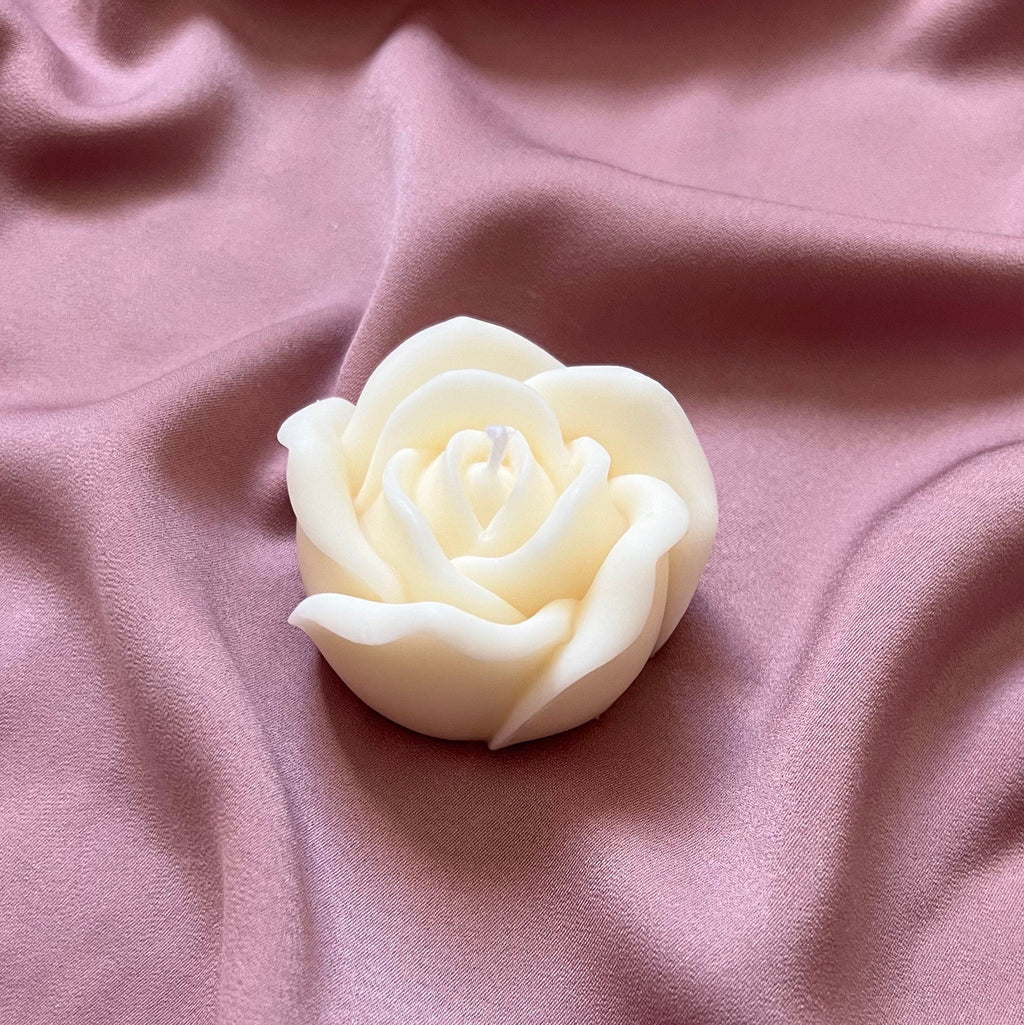 Bougie rose blanche en cire de soja sur un tissu rose