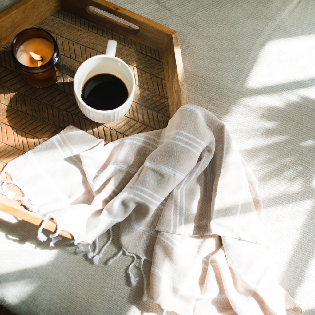 Essuie-mains turc beige sur un plateau en bois avec café et bougie