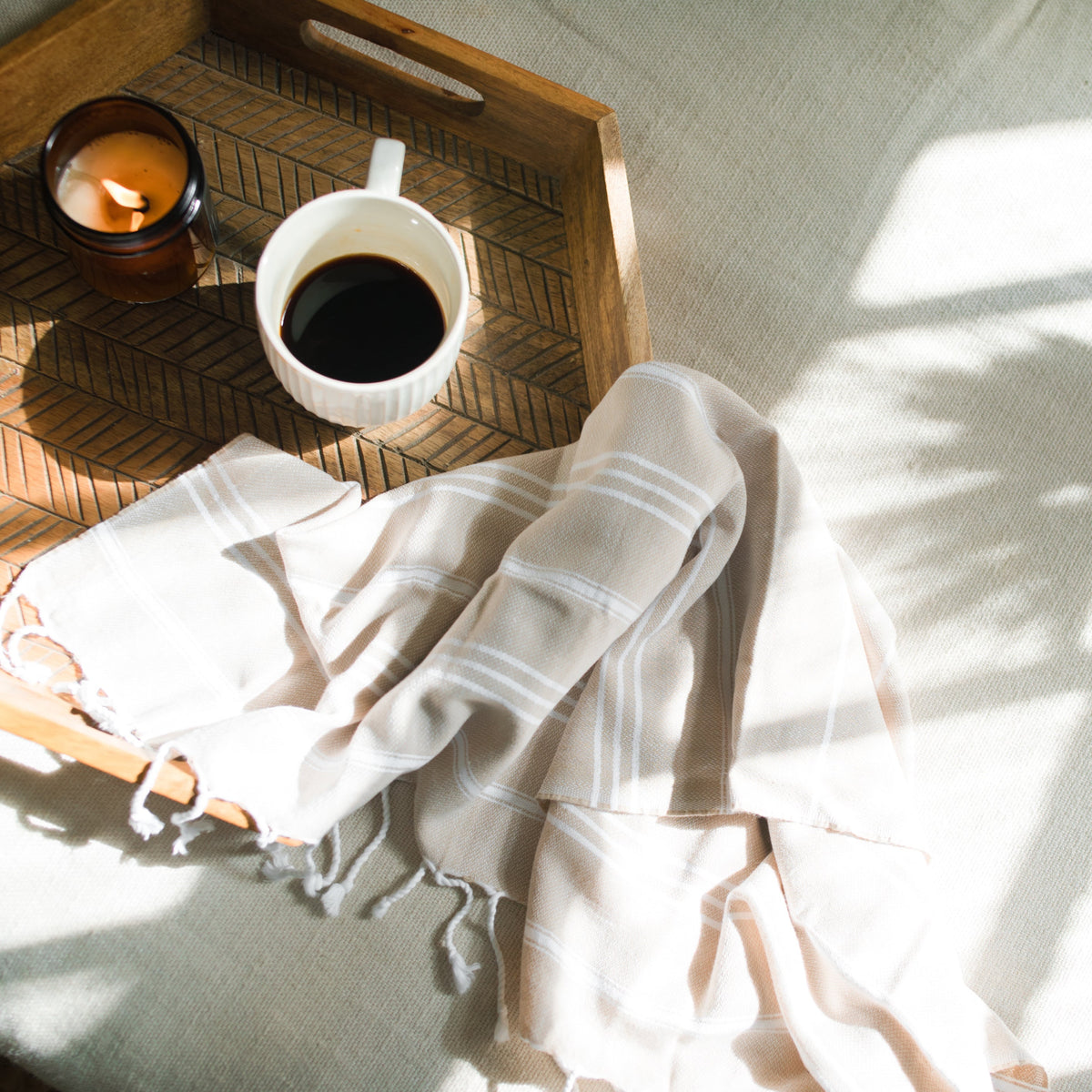 Essuie-mains turc beige sur un plateau en bois avec café et bougie